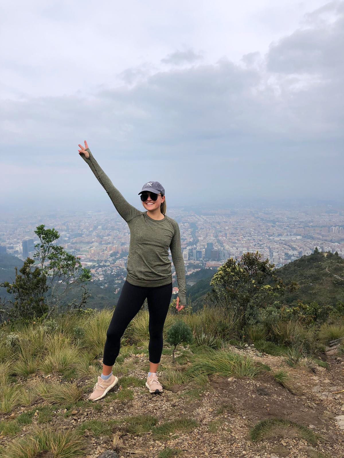 Travel blogger Jessica Sturdy in Bogota, Colombia on a morning hike. She's wearing a Yankees hat, black sunglasses, lululemon longsleeve and leggings, and adidas Ultra Boost gym shoes.