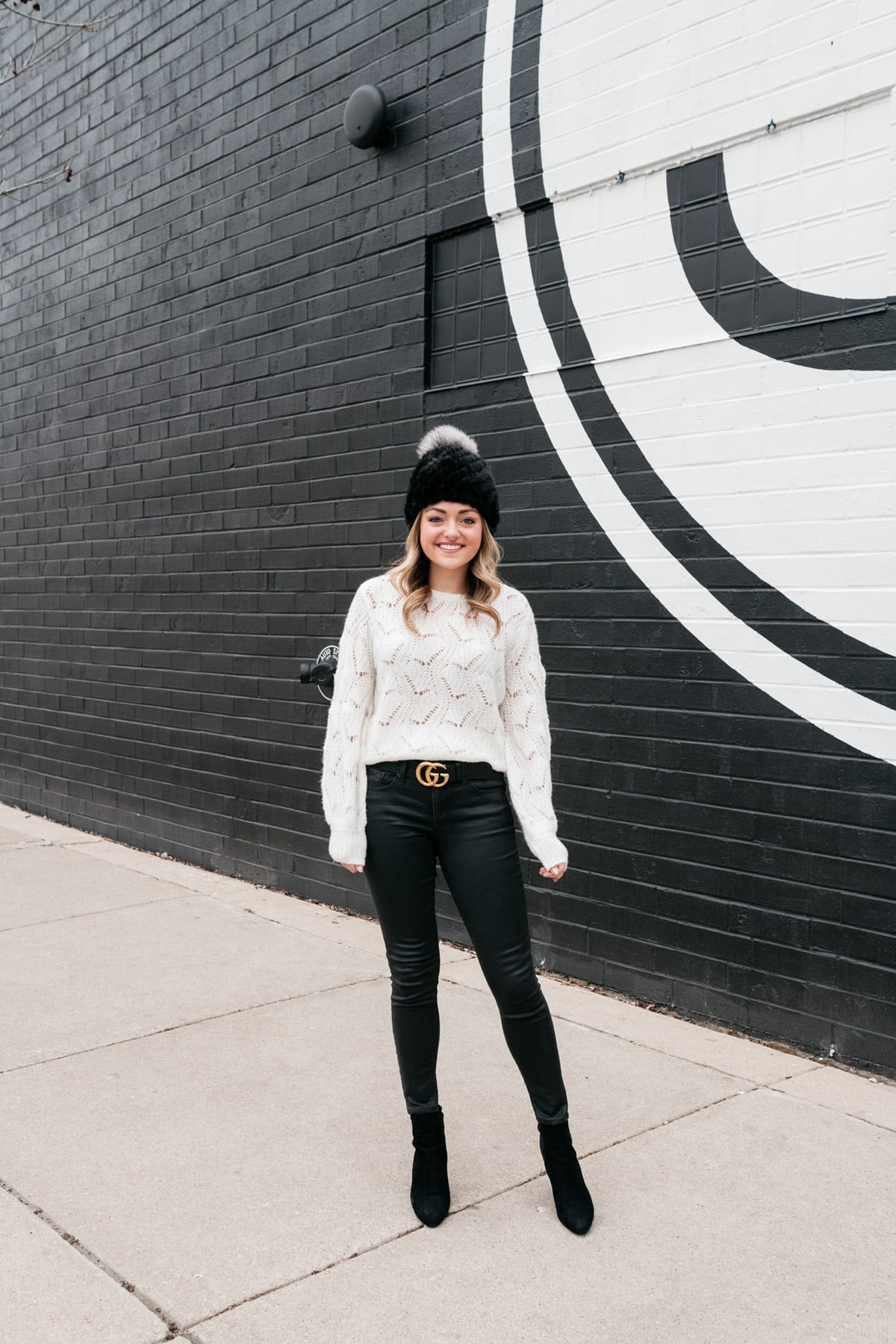 Chicago fashion blogger Jessica Sturdy wearing a fur beanie, Nordstrom sweater, a Gucci belt, coated black jeans, and heeled ankle booties.