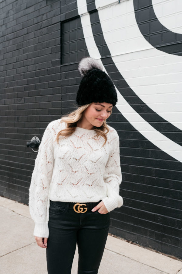 Chicago personal shopper Jessica Sturdy wearing a simple outfit that's elevated with stylish details like a fur beanie, textured sweater, coated jeans, and a logo belt buckle.
