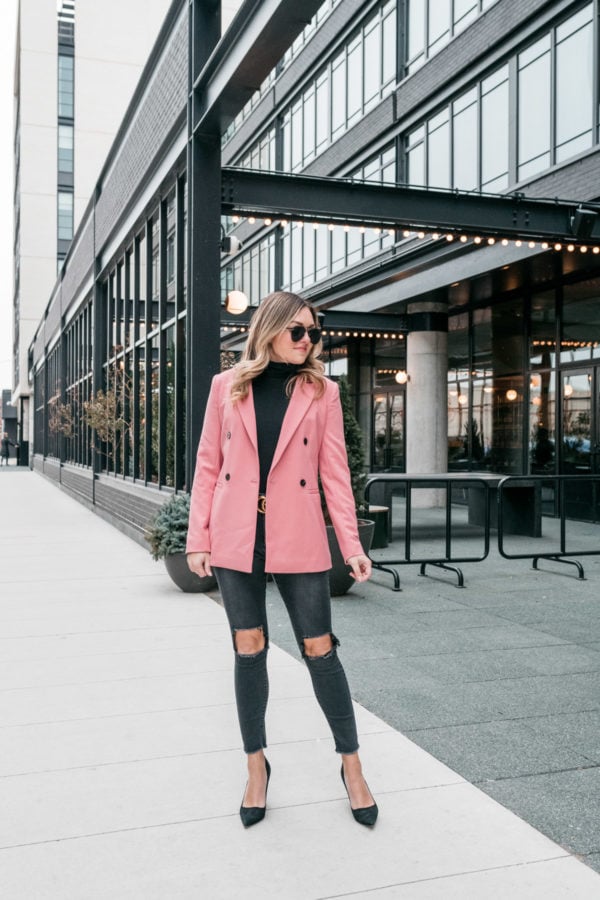 Chicago fashion influencer Jessica Sturdy styles a pink blazer from Nordstrom with a black J.Crew turtleneck bodysuit, One Teaspoon jeans, Kate Spade black pointed pumps, and a black and gold Gucci belt.