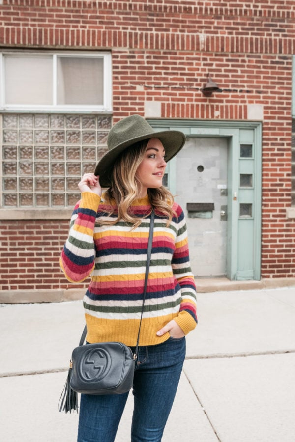Chicago influencer Bows & Sequins wearing a wool hat by Barbour, a cashmere stripe colorful sweater, and a Gucci Soho Disco Bag in navy.