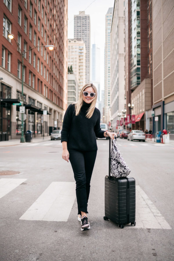 Bows & Sequins styling an all black travel outfit with a MZ Wallace printed tote and an Away Bigger Carry-On.
