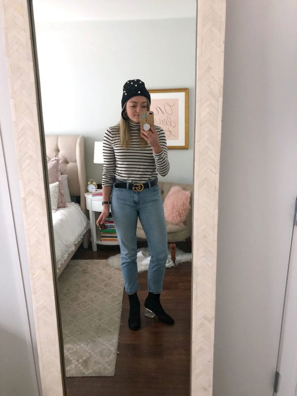 Bows & Sequins wearing a pearl beanie, striped turtleneck, Gucci belt, light wash mom jeans, and lucite heel booties.