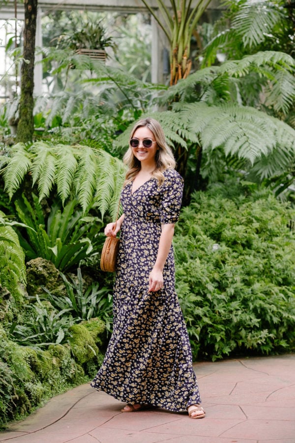 Women's fashion blogger Bows & Sequins shares a summer outfit idea. She is wearing a v-neck floral maxi dress with puff sleeves.