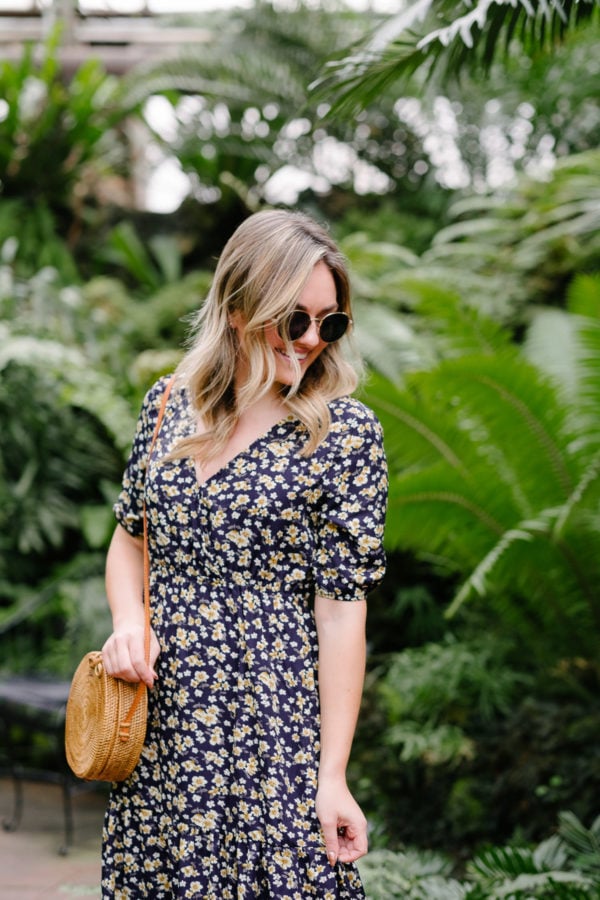 Fashion blogger Jessica Sturdy styles a floral maxi dress with a round rattan bag and small sunglasses for summer outfit ideas on Pinterest.