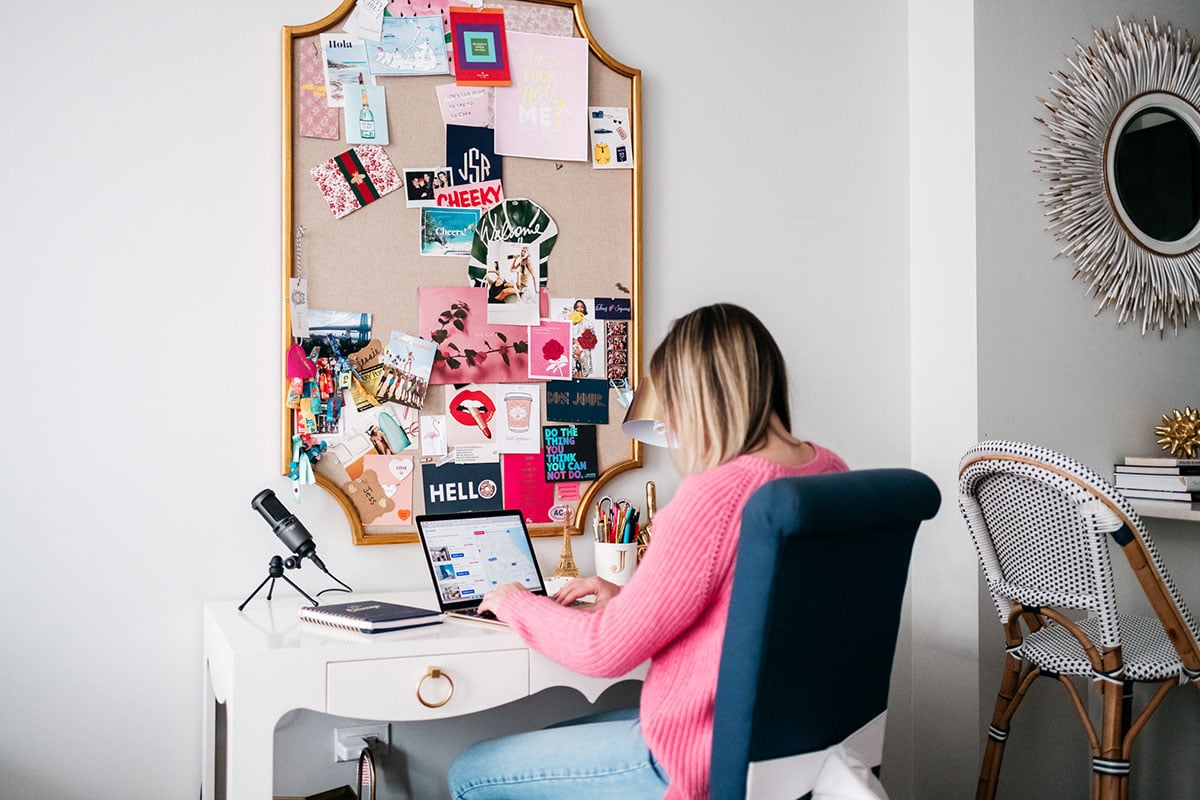 Bows & Sequins sitting at her Bungalow 5 desk in Chicago with a gold memo board and a gold Macbook.