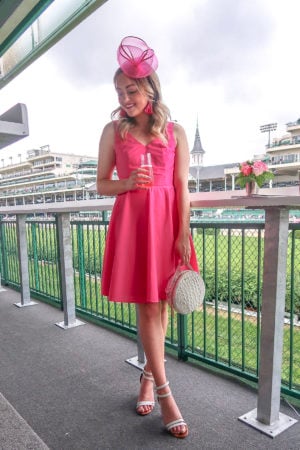 Blogger Bows & Sequins at the Kentucky Derby wearing a pink Vineyard Vines Dress, round Brahmin Bag, and white ankle strap sandals.