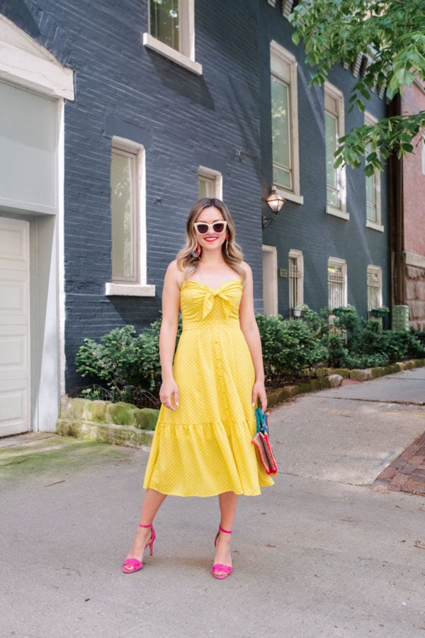 Fashion and beauty blogger Jessica Sturdy styling a yellow polka dot midi dress with pink heels.