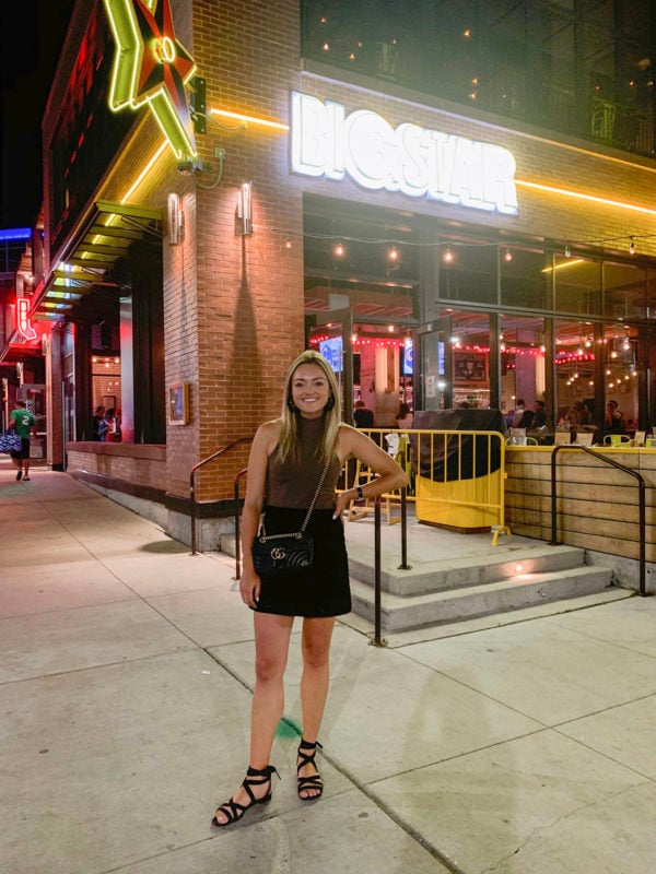 Chicago blogger Jessica Sturdy wearing a mock neck halter bodysuit, suede mini skirt, and M.Gemi ankle wrap sandals, and a Gucci Marmont crossbody bag in front of Big Star in Chicago before a concert.