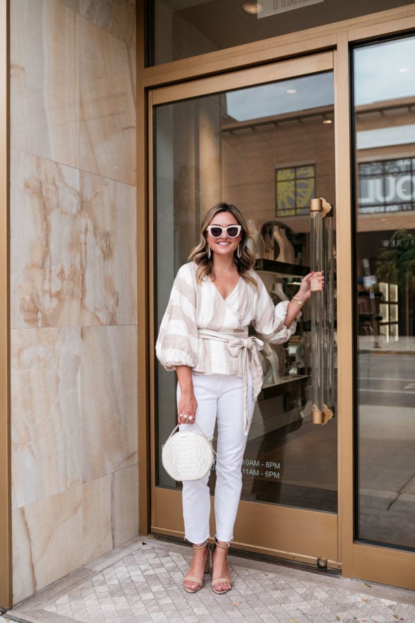 Chicago stylist Jessica Sturdy of Bows & Sequins wearing creamy neutrals for a chic fall outfit. She's wearing a Mara Hoffman linen striped top, white straight leg denim from Vineyard Vines, Kendra Scott jewelry, a Brahmin handbag, and Kenneth Cole nude ankle strap sandals with a block heel.