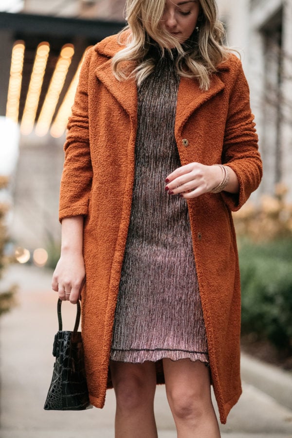 Outfit blogger wearing a brown teddy coat with a party dress.