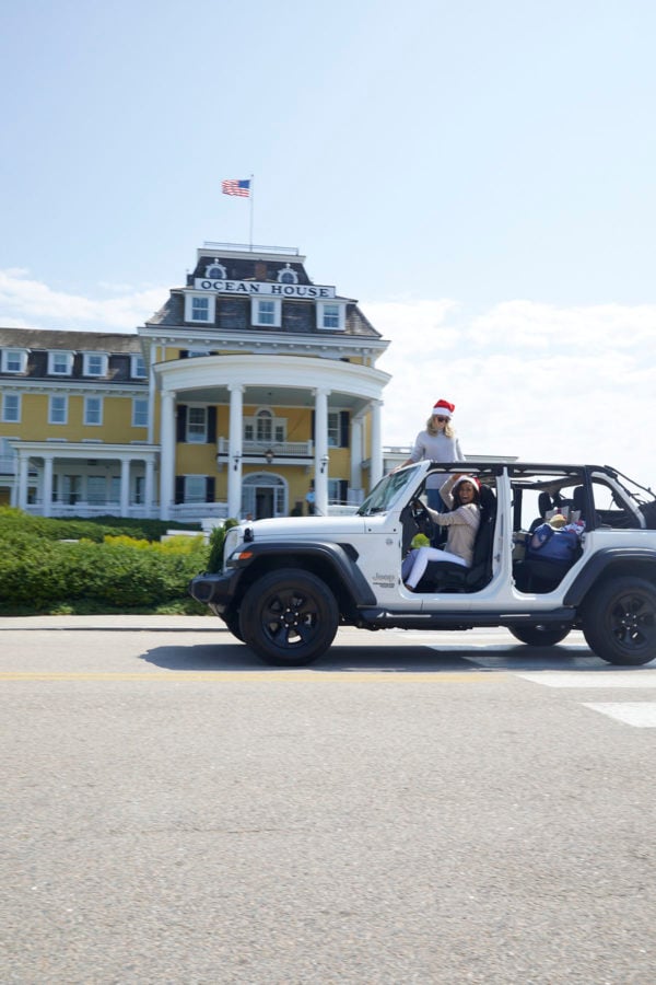 Jessica Sturdy and Caila Quinn driving a white Jeep in Santa hats in front of Ocean House Rhode Island. 