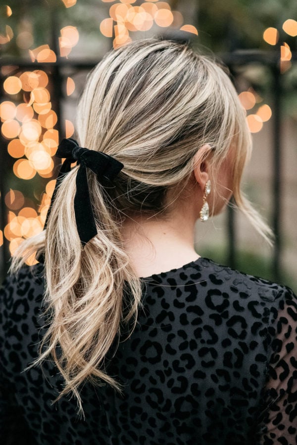 Fashion influencer Jessica Sturdy of Bows & Sequins wearing a black velvet hair bow with blonde curls.
