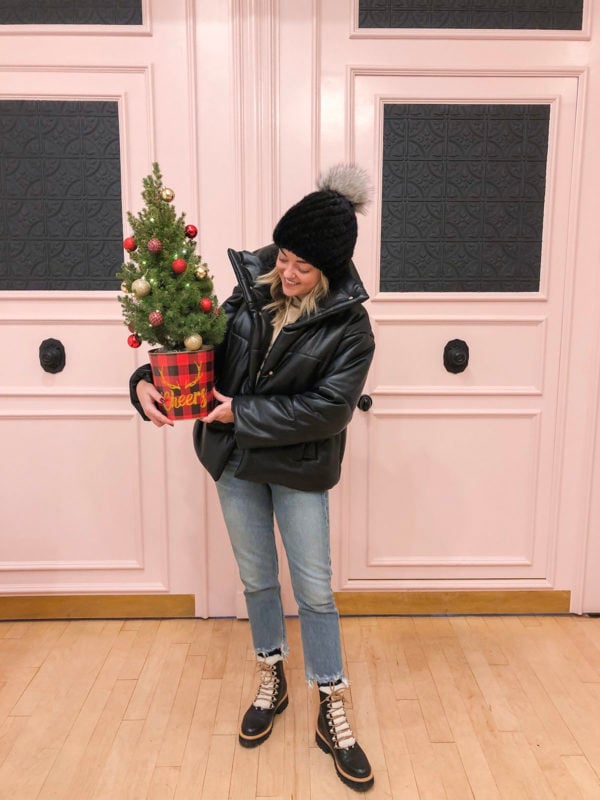 Fashion and lifestyle blogger Bows & Sequins styling a fur pom-pom beanie with a Nanushka leather puffer coat and a Marc Fisher black leather Izzy booties.