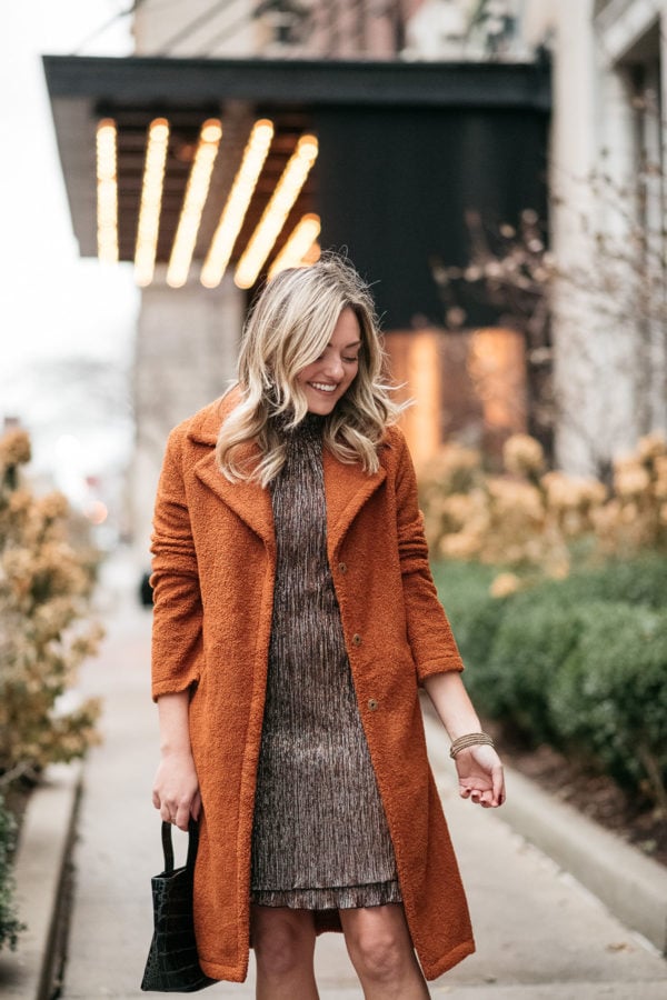 Fashion and beauty blogger wearing a shimmery copper and silver dress with a teddy coat for the holidays.