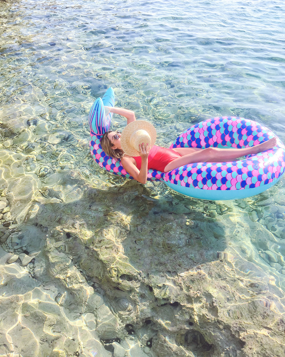 Jessica Sturdy wearing a Summersalt swimsuit floating on a mermaid tail pool float in the clear water off of the Palisinki Islands in Hvar Croatia