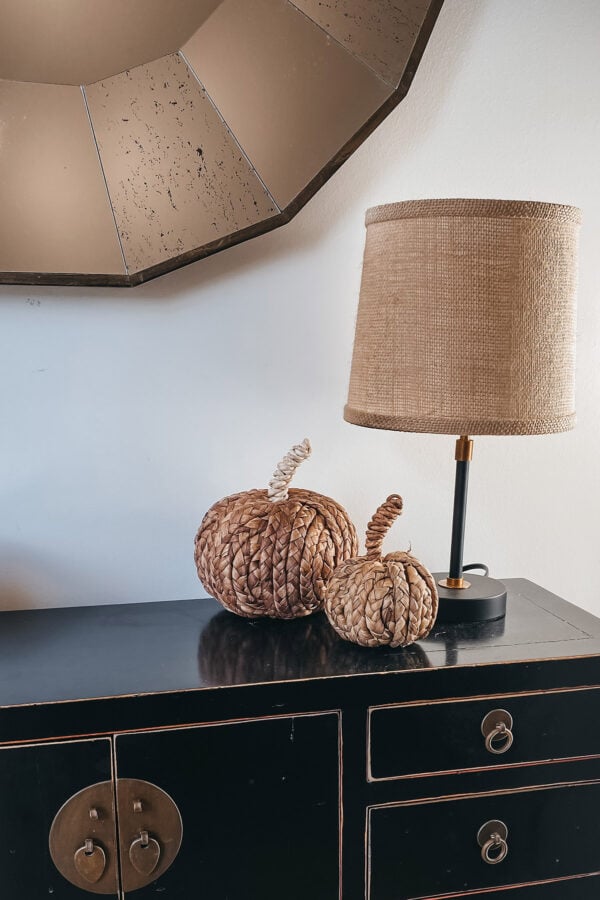Fashion, home, & lifestyle blogger Jessica Sturdy of Bows & Sequins shares her modern fall decor featuring her entryway console table with a mini lamp with a raffia lampshade and neutral pumpkins.
