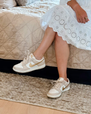 Jessica Sturdy of Bows & Sequins wearing a white eyelet dress with Nike Dunks in Phantom Metallic Gold.