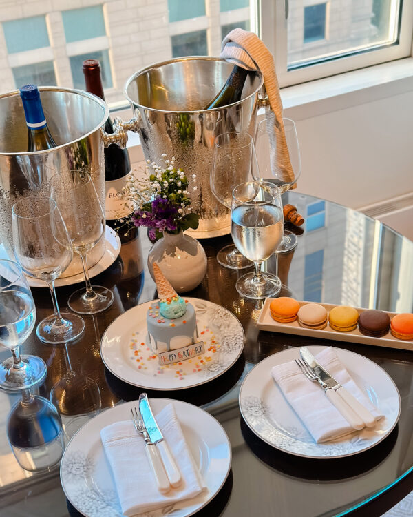 Birthday treat Ice Cream Cone cake with colorful macarons on a table at the Peninsula hotel in Chicago with a bottle of Dom Perignon in a silver ice bucket.