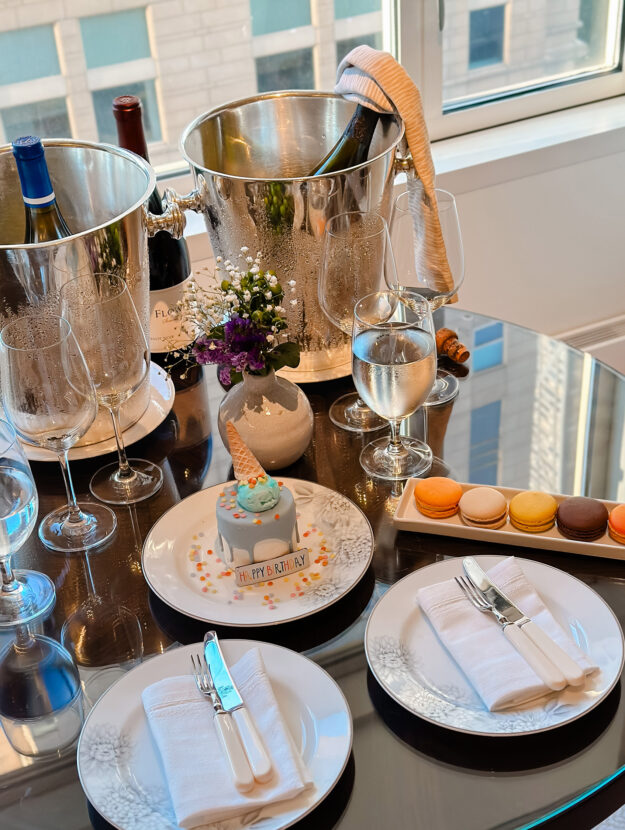 Birthday treat Ice Cream Cone cake with colorful macarons on a table at the Peninsula hotel in Chicago with a bottle of Dom Perignon in a silver ice bucket.