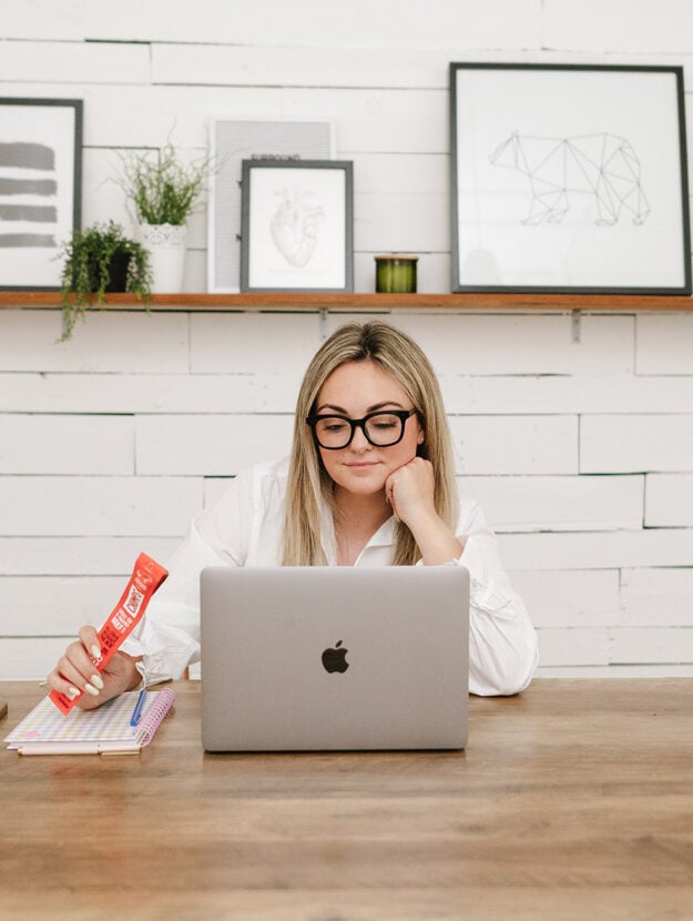 Jessica Sturdy of Bows & Sequins shares her Cyber Week Guide. Photo is of her sitting at a silver computer with a Chomps meat stick.
