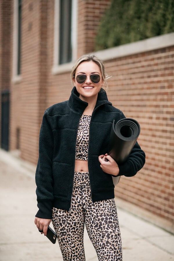 Lifestyle blogger wearing a leopard Outdoor Voices workout set with a Vineyard Vines black sherpa coat and Lululemon Yoga Mat. The blog post details her Class Pass review.