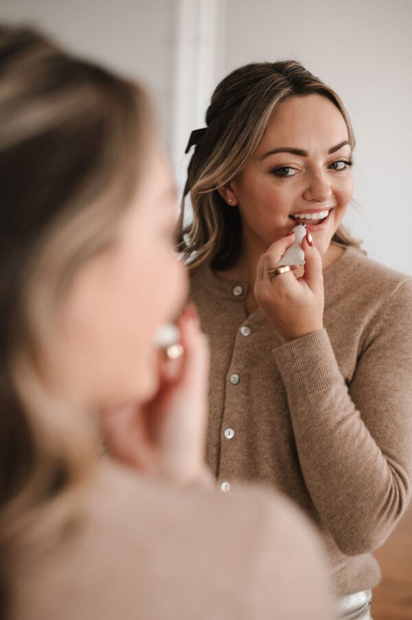 Chicago influencer Jessica Sturdy of Bows & Sequins applying a lip treatment in the mirror.