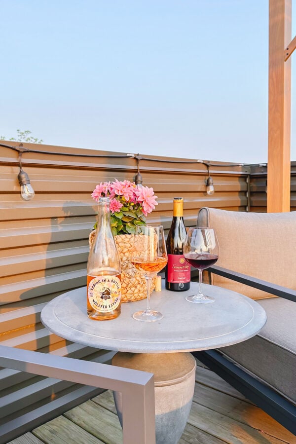 Wellness blogger Jessica Sturdy of Bows & Sequins shares about her sober curiosity and what she's realized from not drinking. Pictured is a bottle of non-alcoholic sparkling rosé next to a bottle of red wine on a patio at sunset.