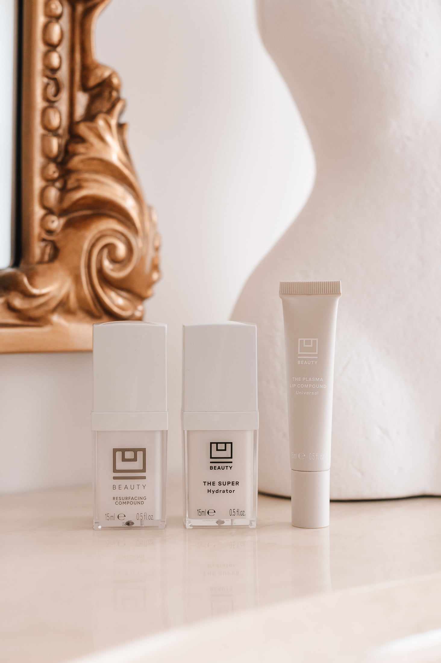 U Beauty Resurfacing Compound and Super Hydrator skincare bottles and Lip Plasma tube on a marble mantle