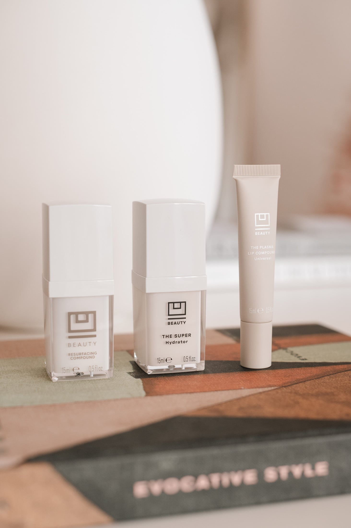 U Beauty Resurfacing Compound and Super Hydrator skincare bottles and Lip Plasma tube on a Kelly Wearstler book